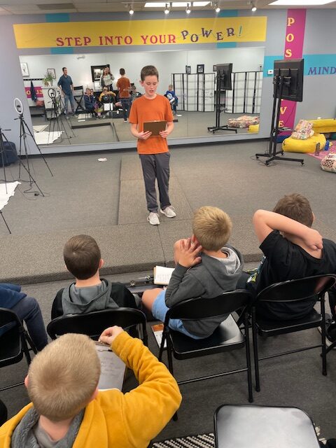Young boy speaking in front of a crowd at Fearless Focus. The boys program focused on social-emotional growth.